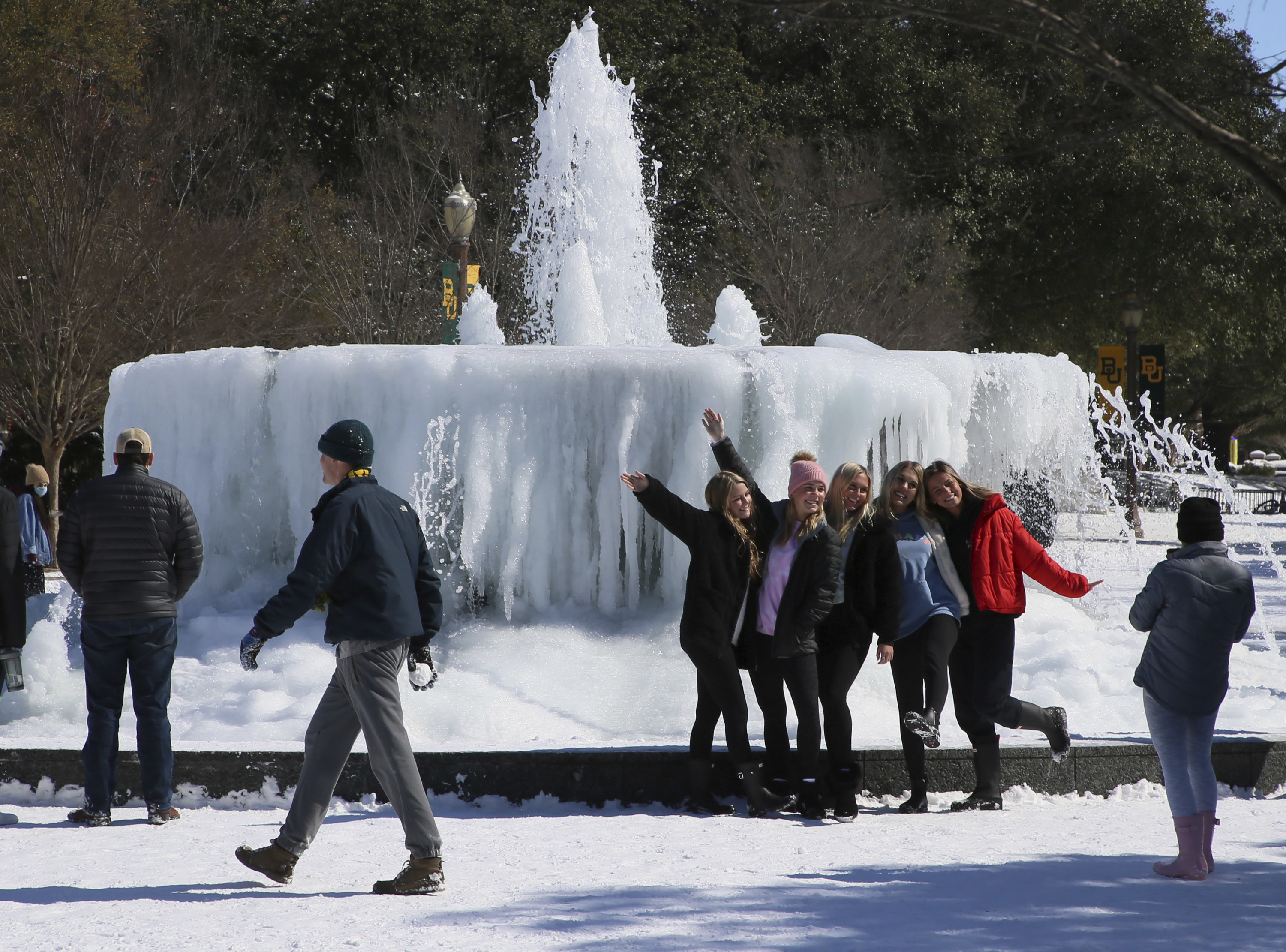 A group of young women posing for a photo together in front of a frozen fountain