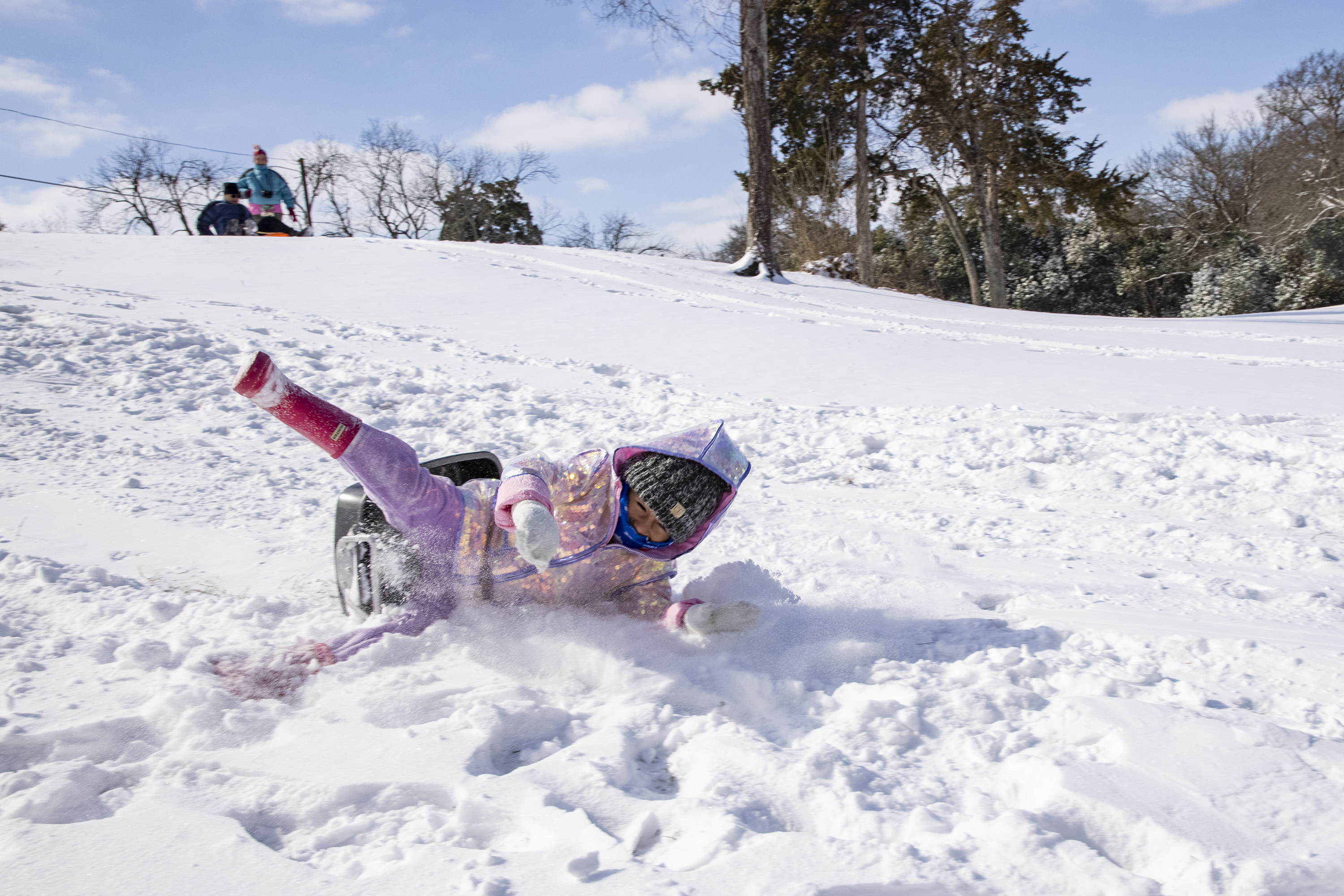 A young girl sledding down a hill