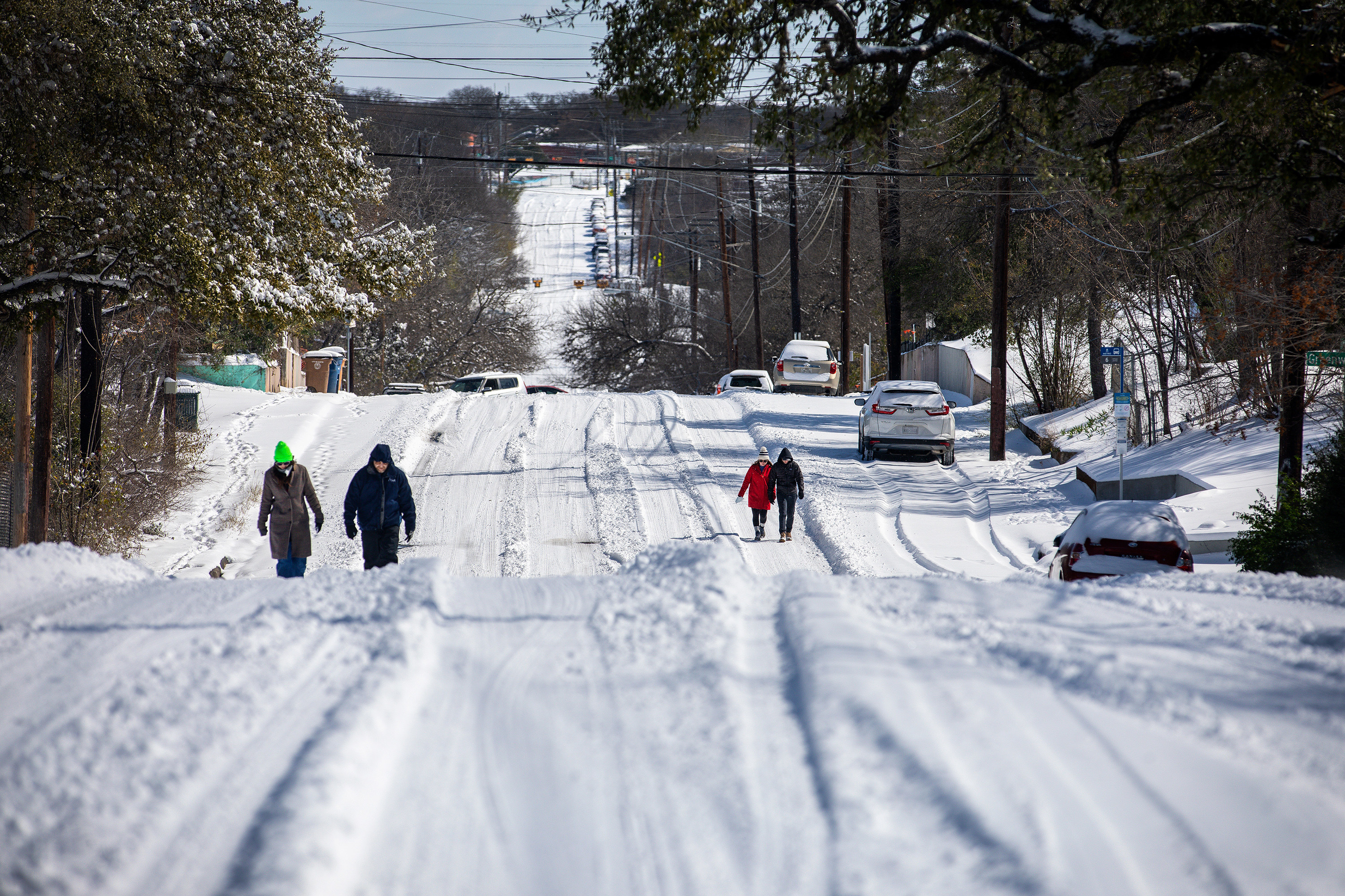 Two pairs of people walking down extremely snowy roads in Texas