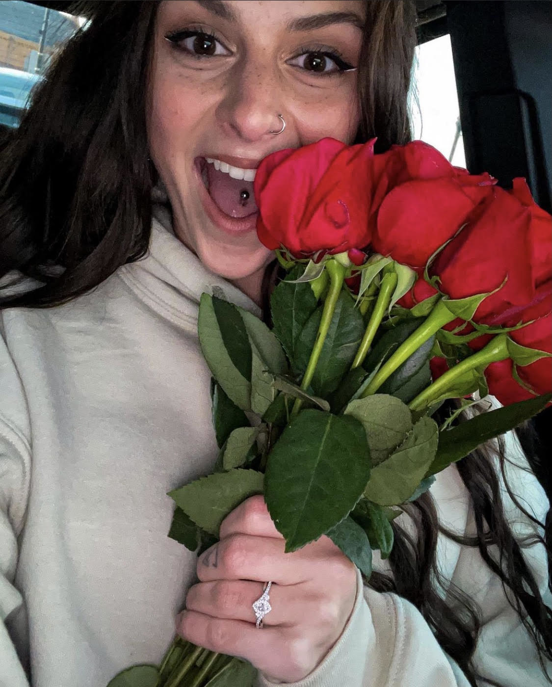 Danielle widely smiles as she holds a bouquet of roses and shows off an engagement ring