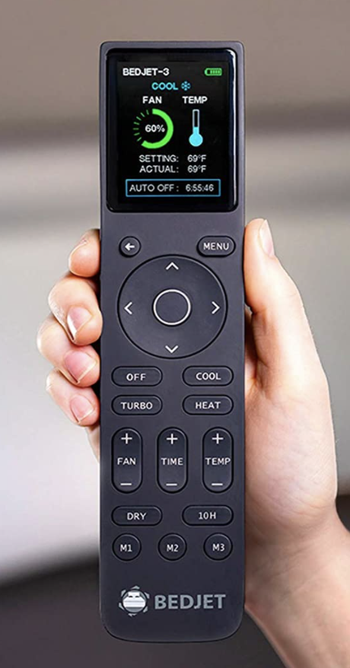 a hand holding the black remote which has a digital screen