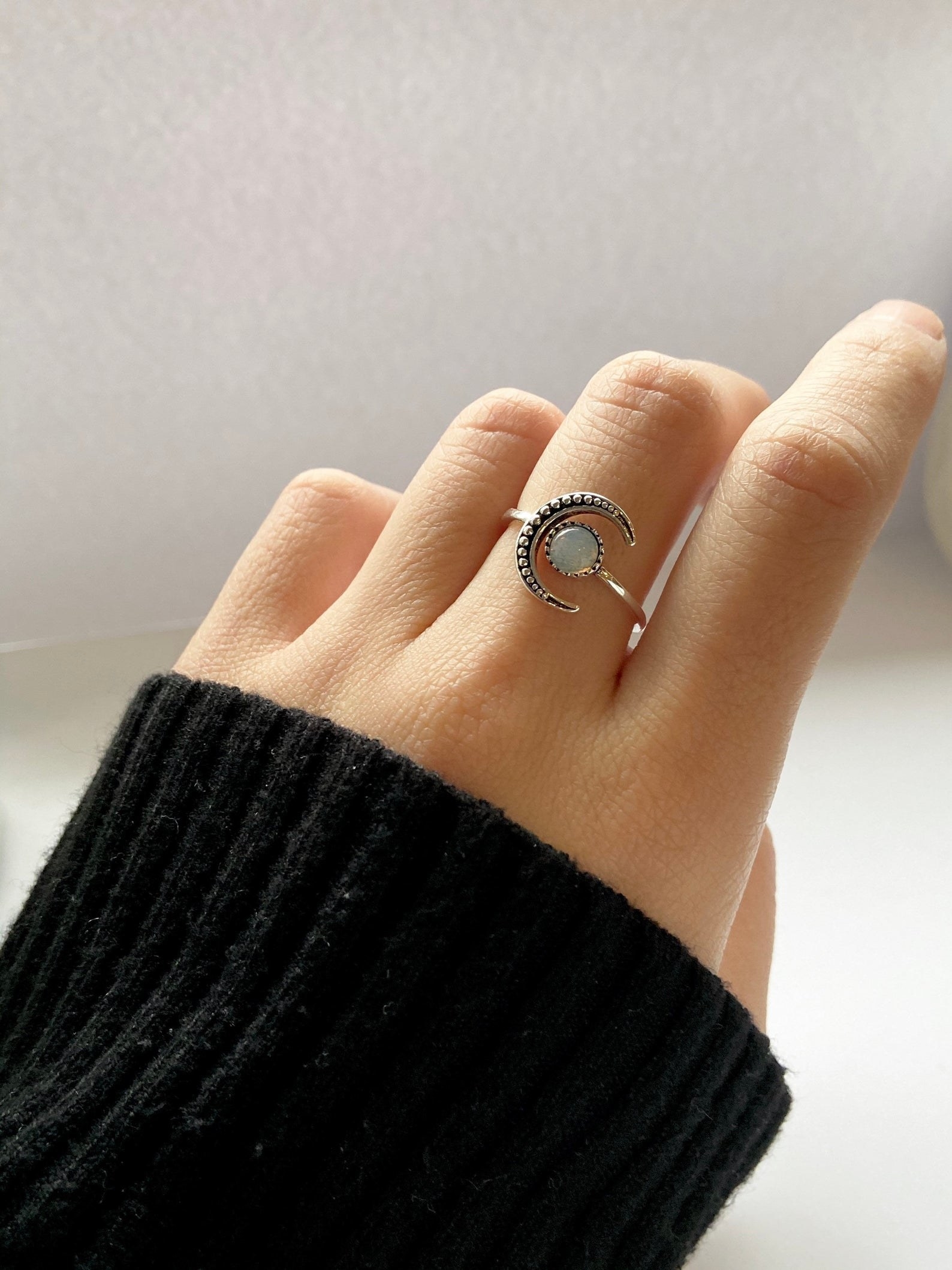 a hand with the crescent moon stone ring on the middle finger