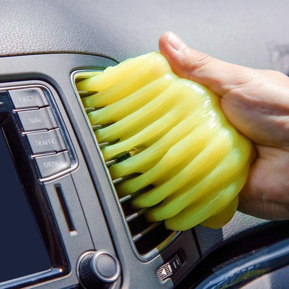 A person using the slime to clean their car vents