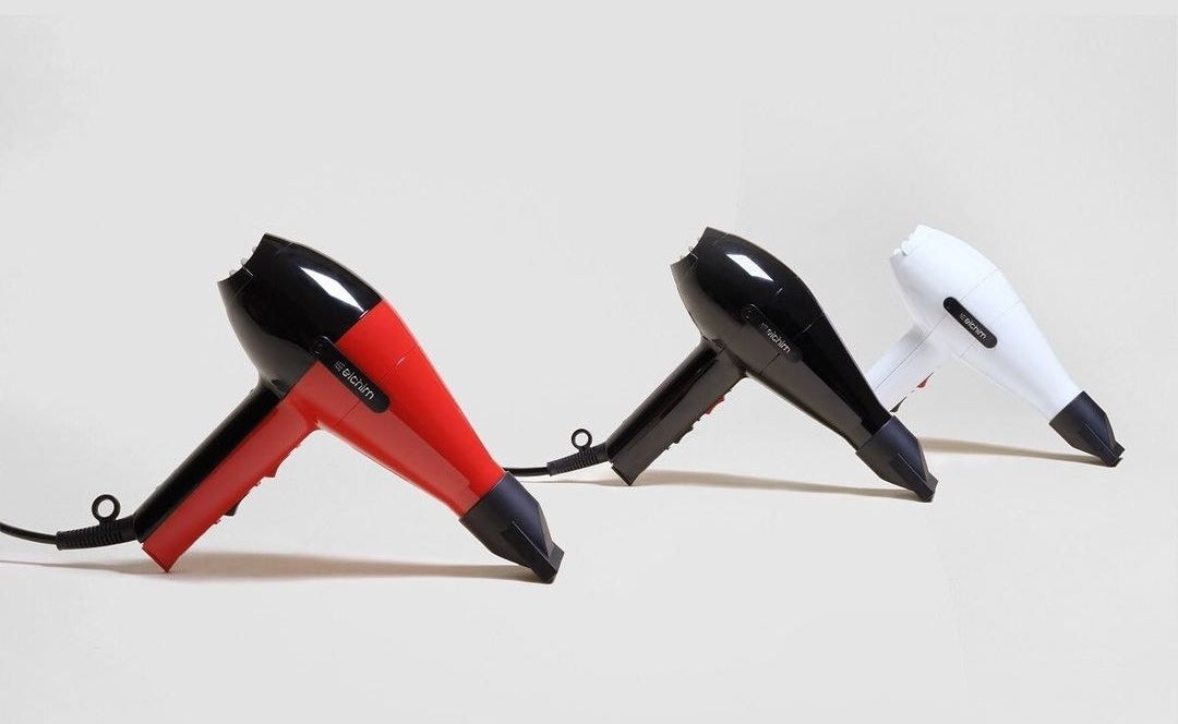 a red/black, black, and white hairdryer with a thin nozzle on the end
