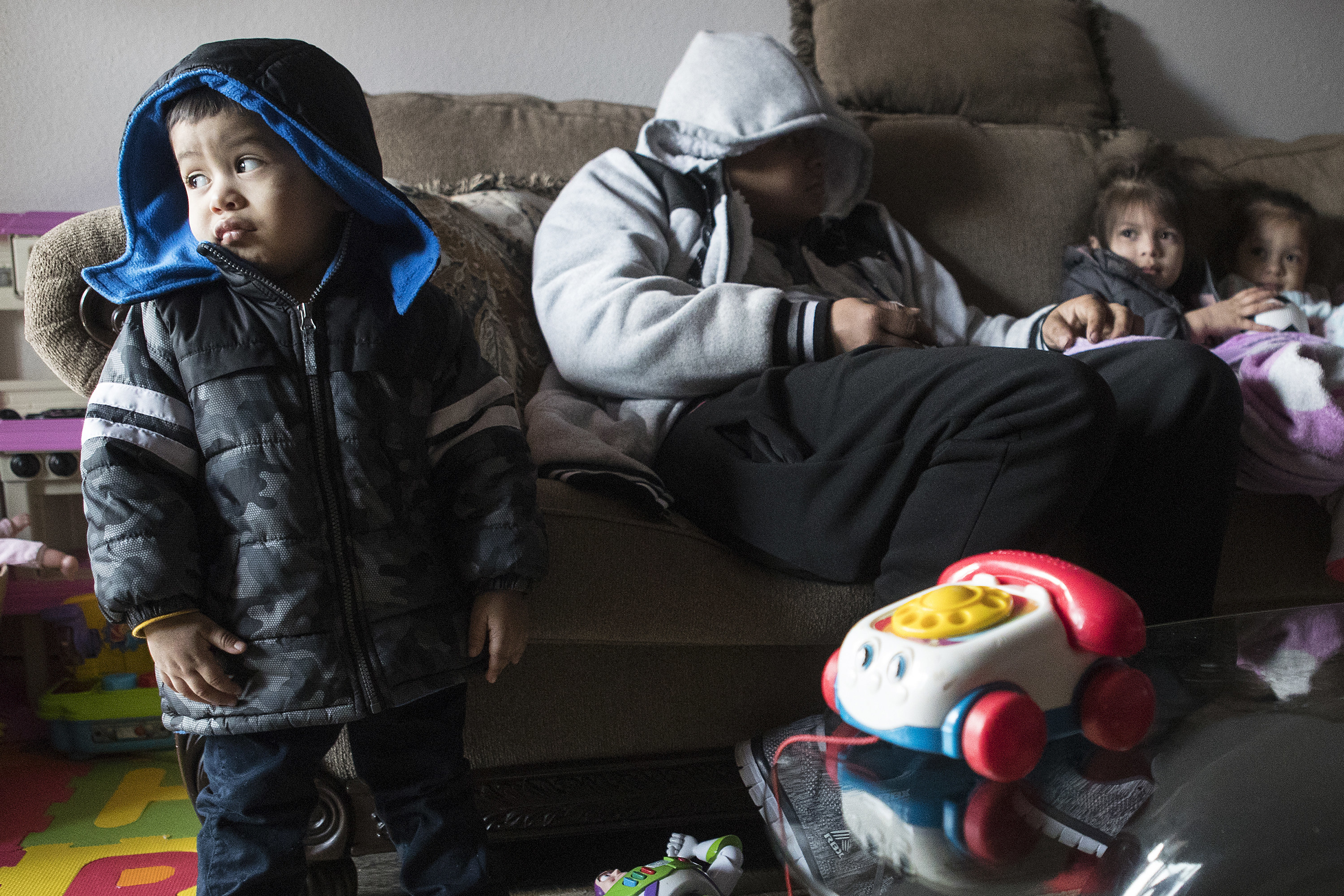 A family of one man and three children wearing winter coats indoors