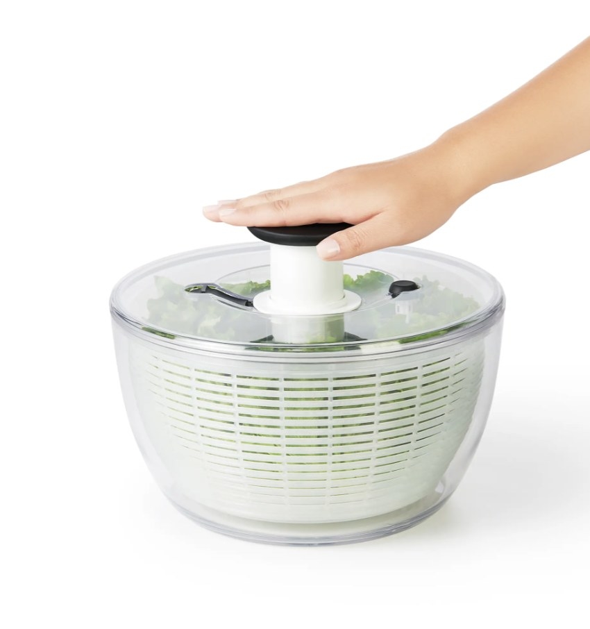 Person is pushing the level on a white salad spinner