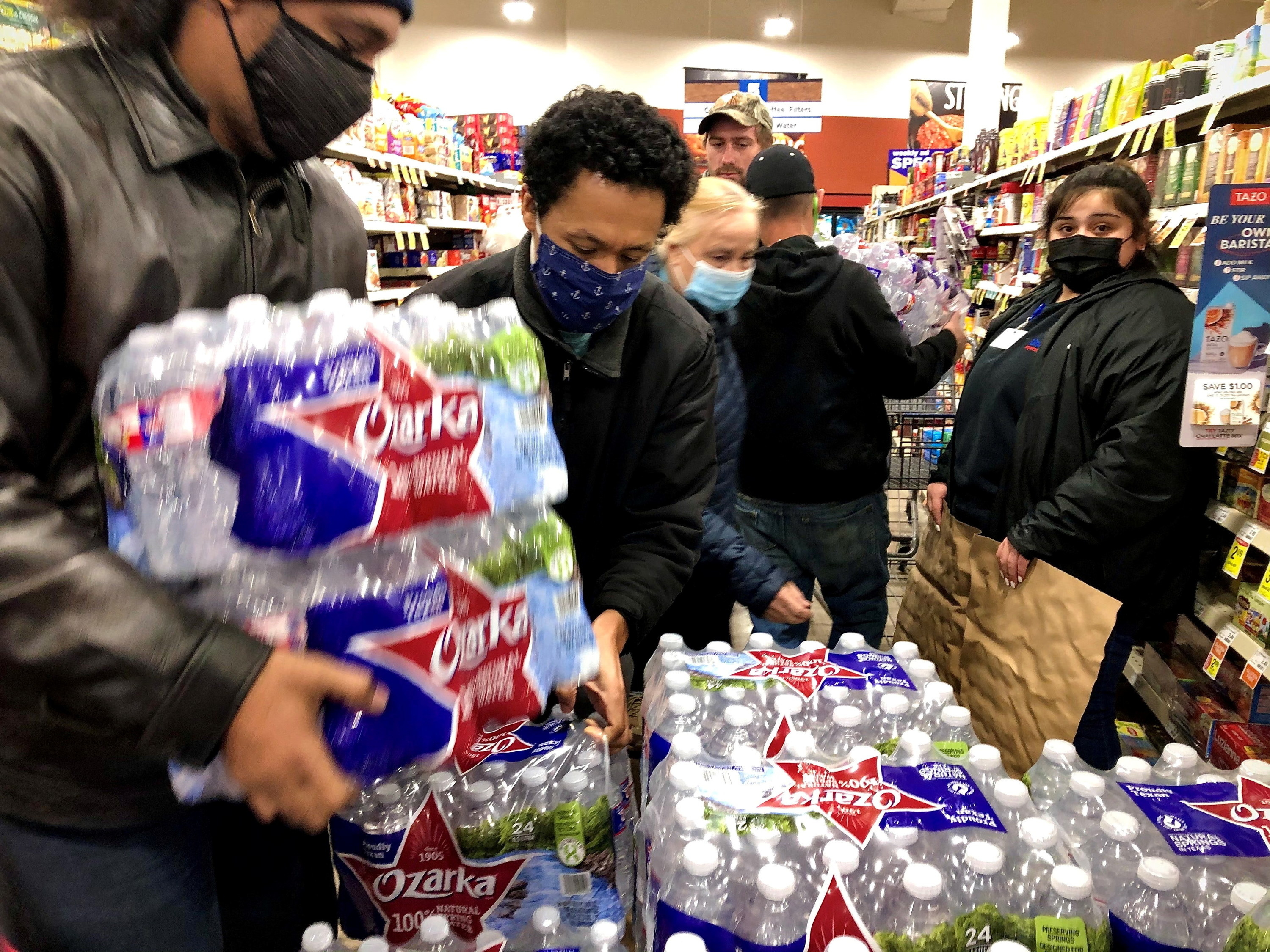 People grabbing at cases of water in a supermarket