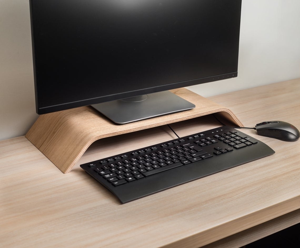 Sleek curved riser with keyboard beneath it and computer monitor on top 