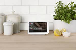 Nest Hub on countertop with lemons and herbs with video on screen about how to cut a pineapple. 