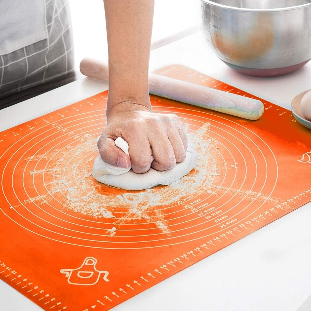A person slamming dough down on the mat