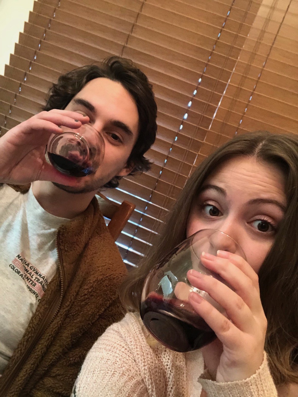 Young man and woman each drinking glasses of red wine