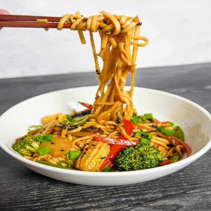 Vegetable lo mein being eaten with chopsticks.