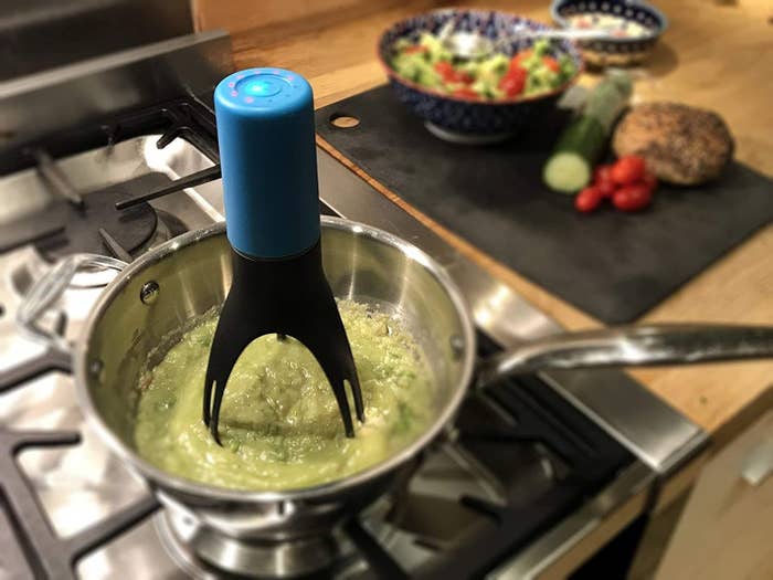 blue and black auto-stirrer in a pot filled with eggs and veggies