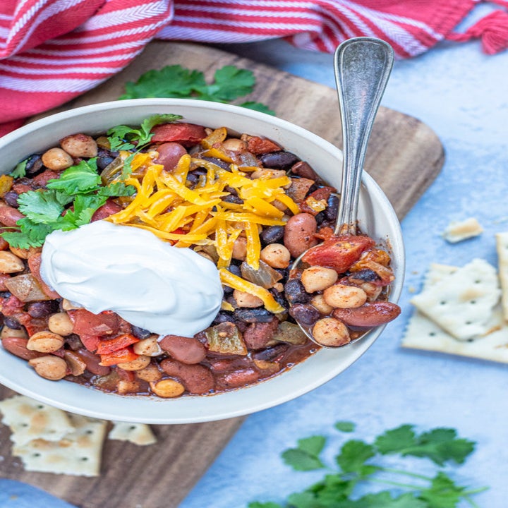 A bowl of bean chili with sour cream and cheese.