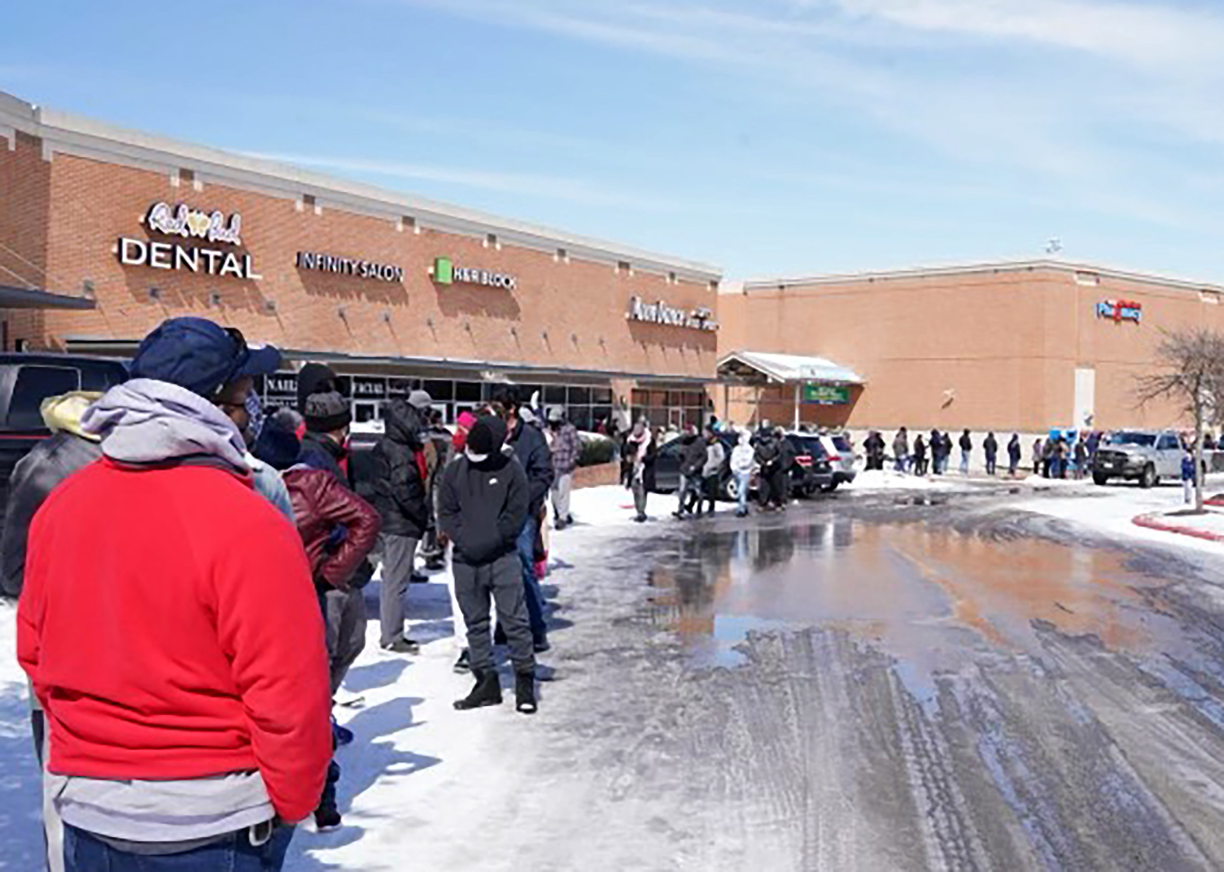 A long line of people waiting outside the supermarket