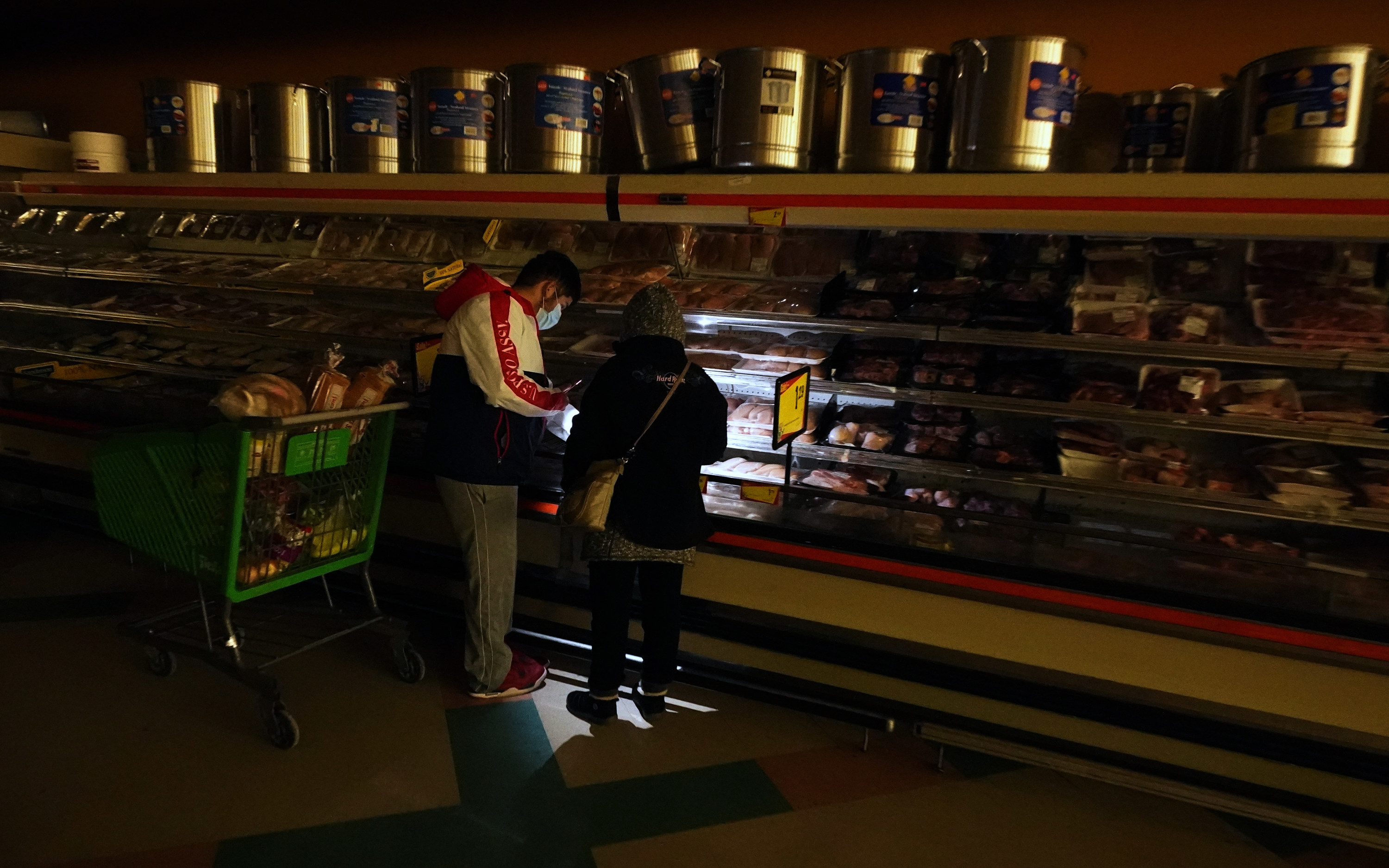 Two people buy meat in a supermarket with a flashlight as the power is out