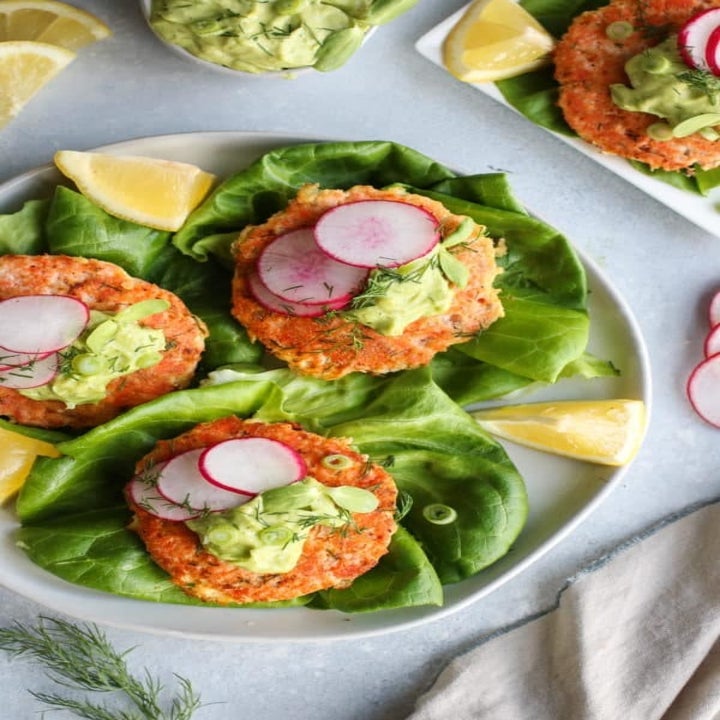 Salmon burgers with avocado sauce in lettuce cups.