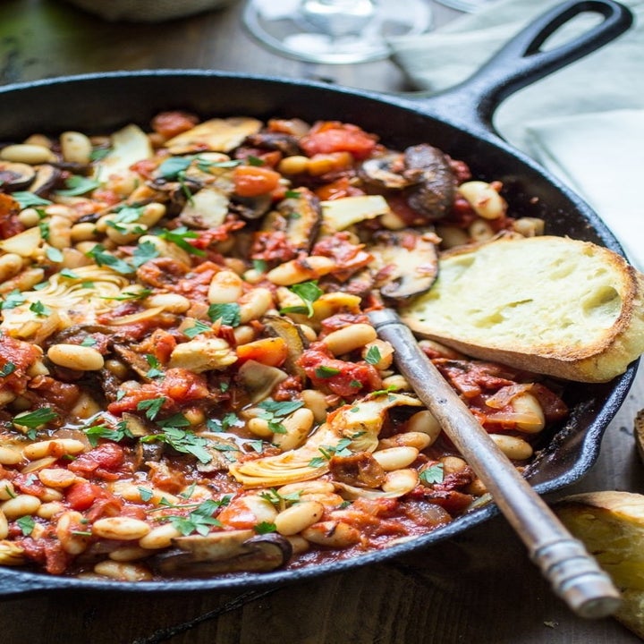 A white bean skillet with tomatoes, mushrooms, spinach, and artichokes.