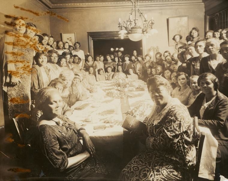 A very aged photograph of a group of women around a table