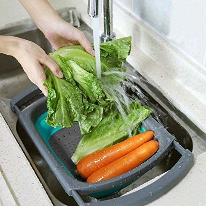 A collapsible colander on a sink with vegetables in it