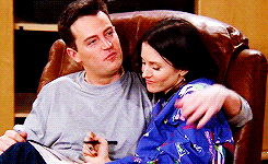 Monica and Chandler sitting on a couch together being cute