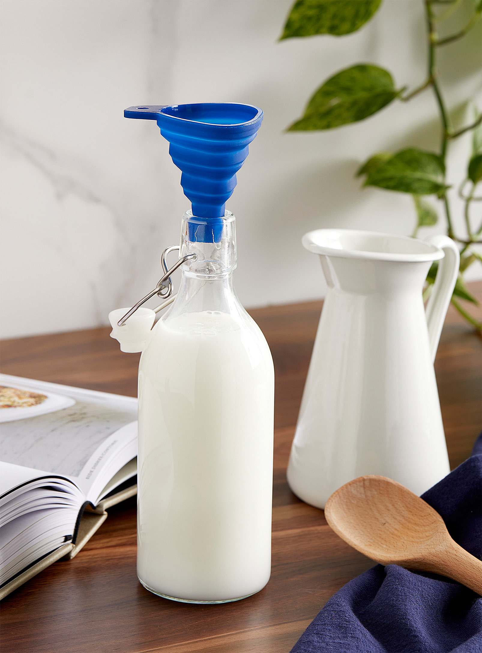 A small silicone funnel balancing on the lip of a glass carafe filled with milk