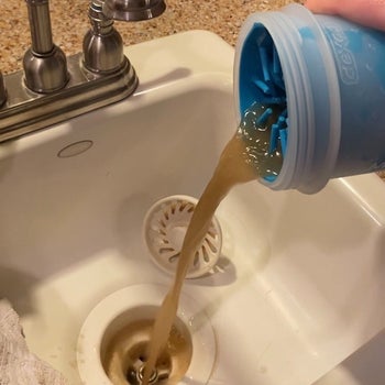 reviewer pouring out the dirty, muddy water from the paw cleaner