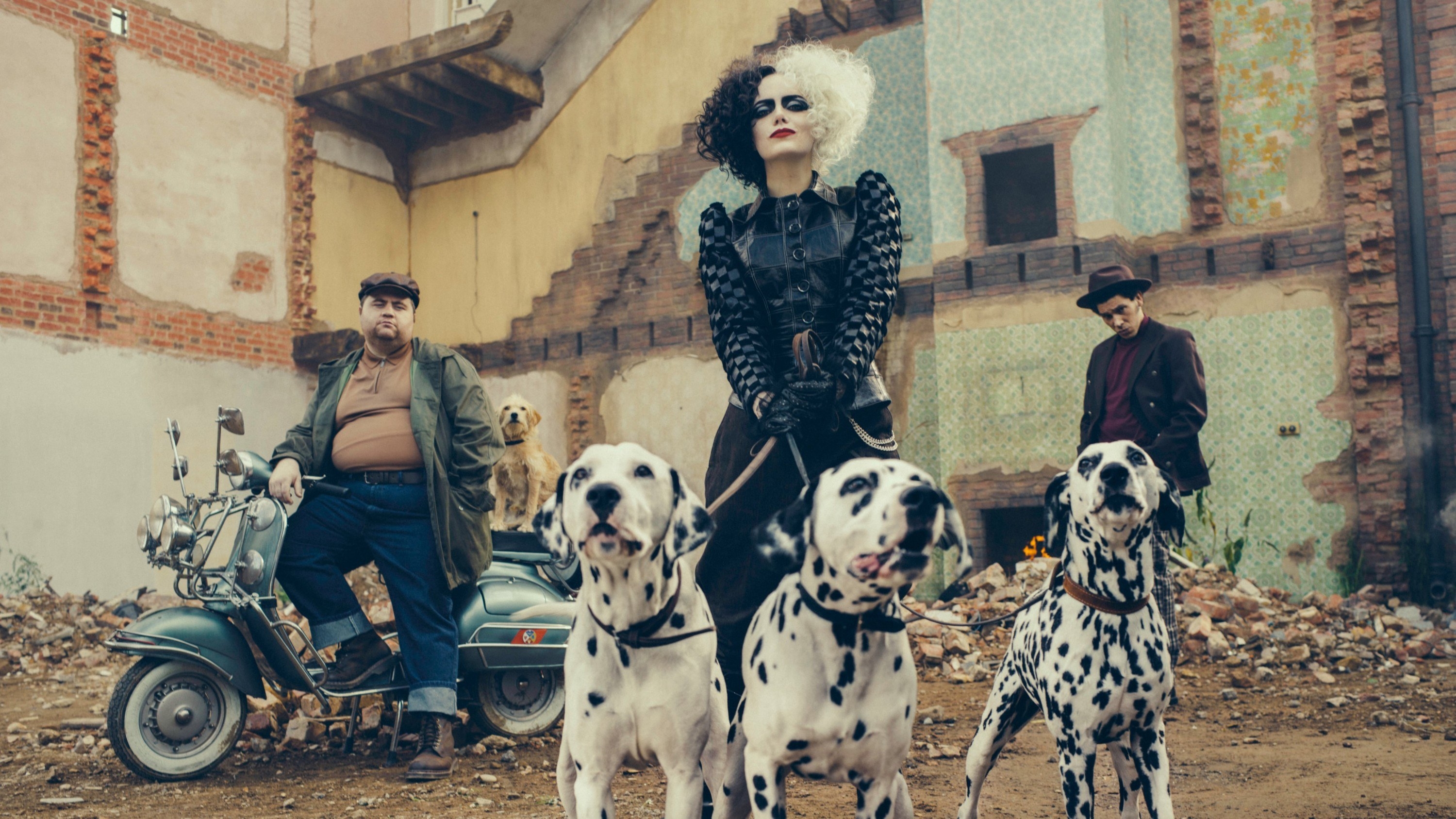 Emma as Cruella de Vil holding the leashes of three Dalmatians in an abandoned yard and two henchmen standing behind her