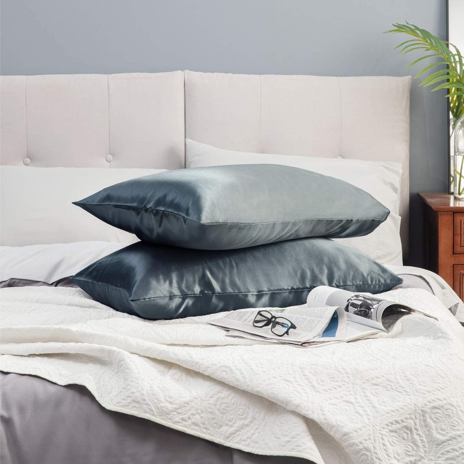 Two pillows inside of satin pillowcases on a bed