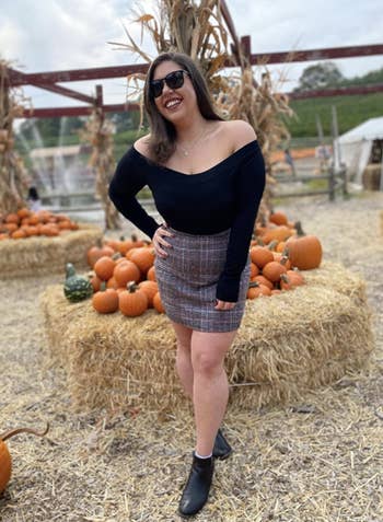 reviewer wearing plaid skirt in pumpkin patch