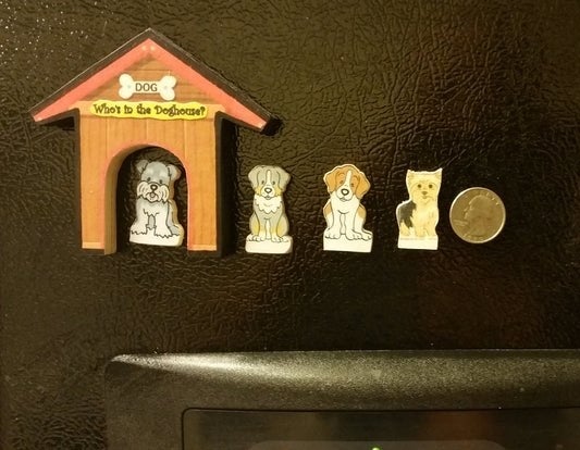 A magnet shaped like a doghouse that says 'Who's in the doghouse?" and four dog-shaped magnets with a quarter next to them for scale