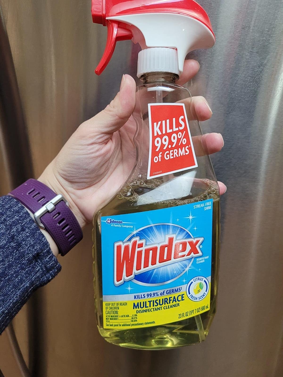 Reviewer holding bottle of Windex multisurface disinfectant cleaner
