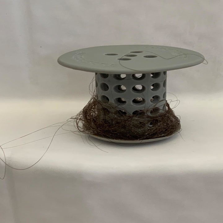 A reviewer photo of the TubShroom removed from the drain with hair wrapped around it 