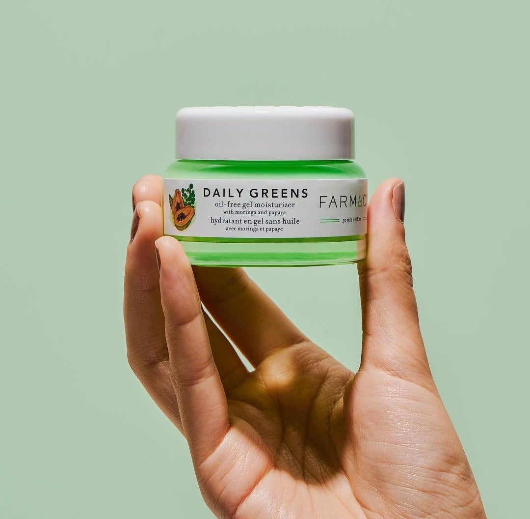 Someone holding up a jar of the product against a colour-coordinated background