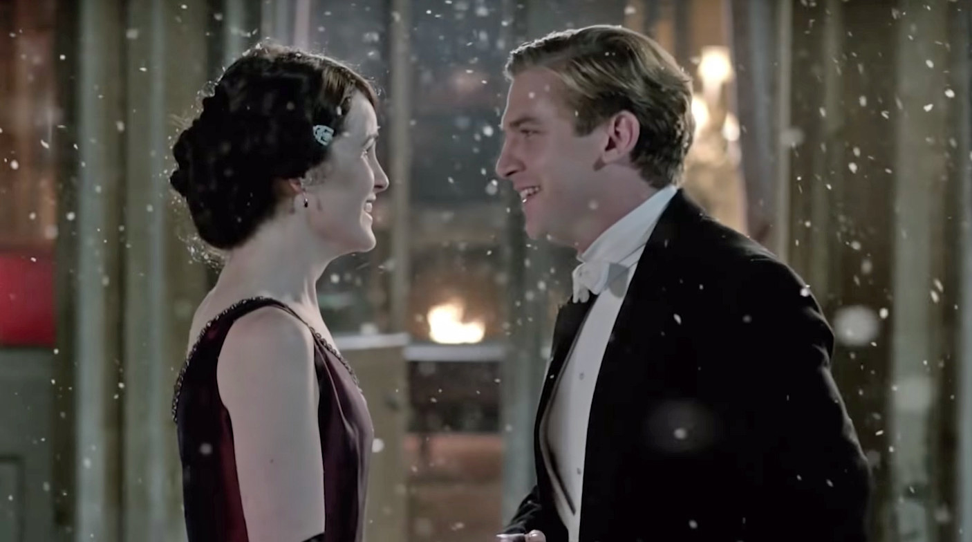 Mary and Matthew smile at each other as the snow comes down around them