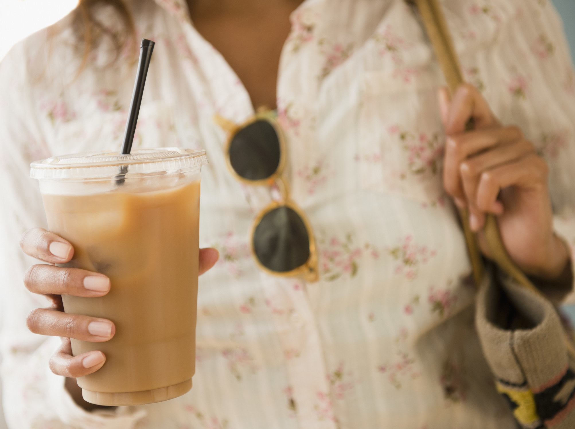 A woman holding an iced coffee drink