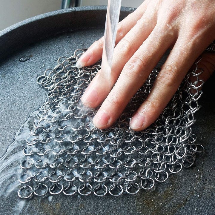 Model using chainmail scrubber on cast iron pan