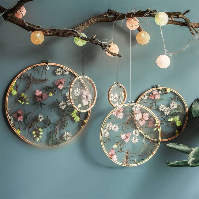 Embroidered flowers in a transparent background in a light wooden hoop hanging from the ceiling 