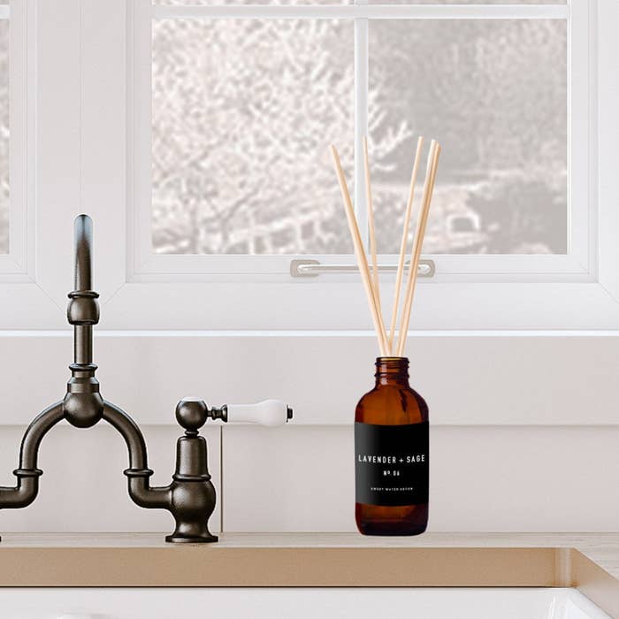 amber bottle of lavender and sage diffuser next to silver faucet