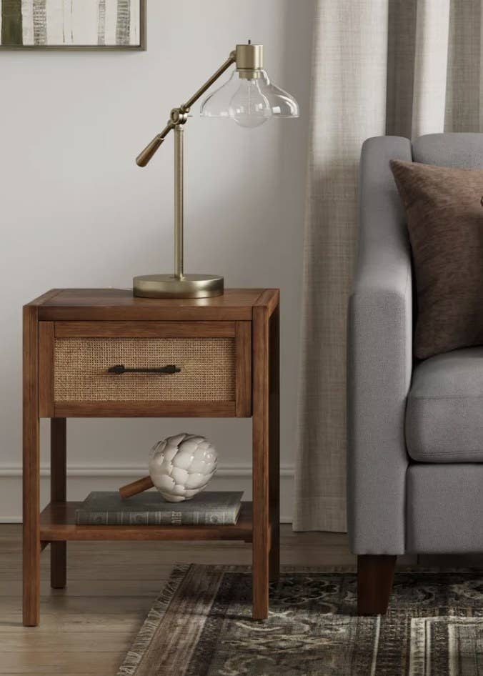 a warwick wood side table with one drawer and one shelf. on the drawer is rattan and black metal hardware
