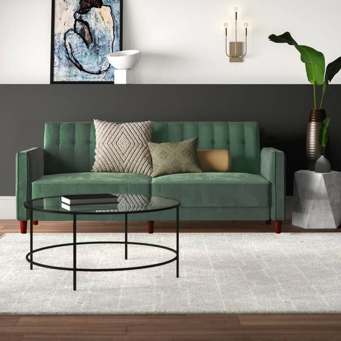The couch in green, which has two wide seat cushions and small wooden legs