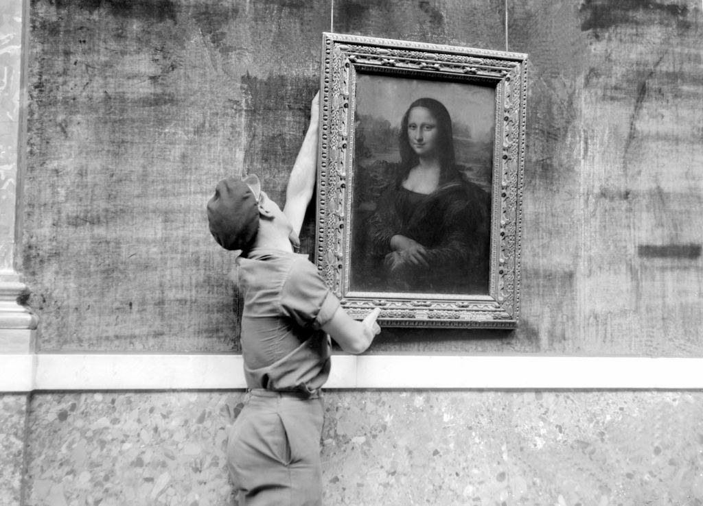 Person hanging the Mona Lisa painting on a wall