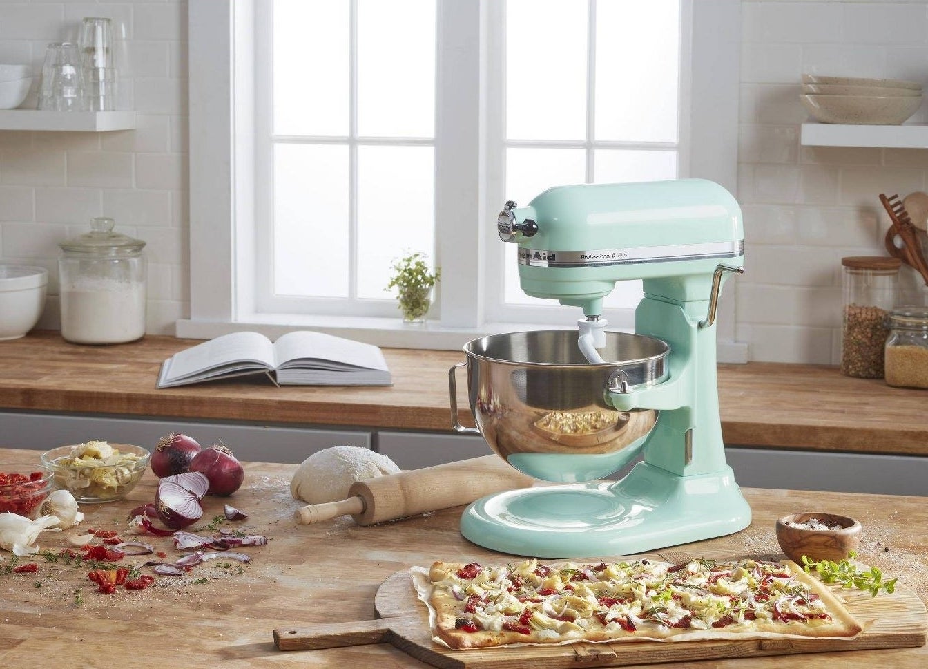 The mixer on a countertop with a pizza and ingredients