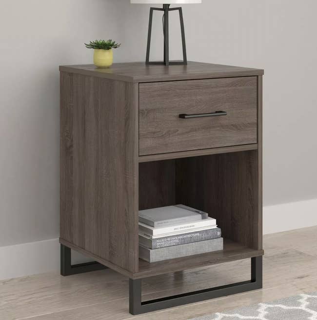 a grey-brown mixed-material nightstand with one drawer and one shelf