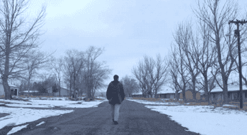 GIF of Fern walking alone on a desolate road in the dead of winter