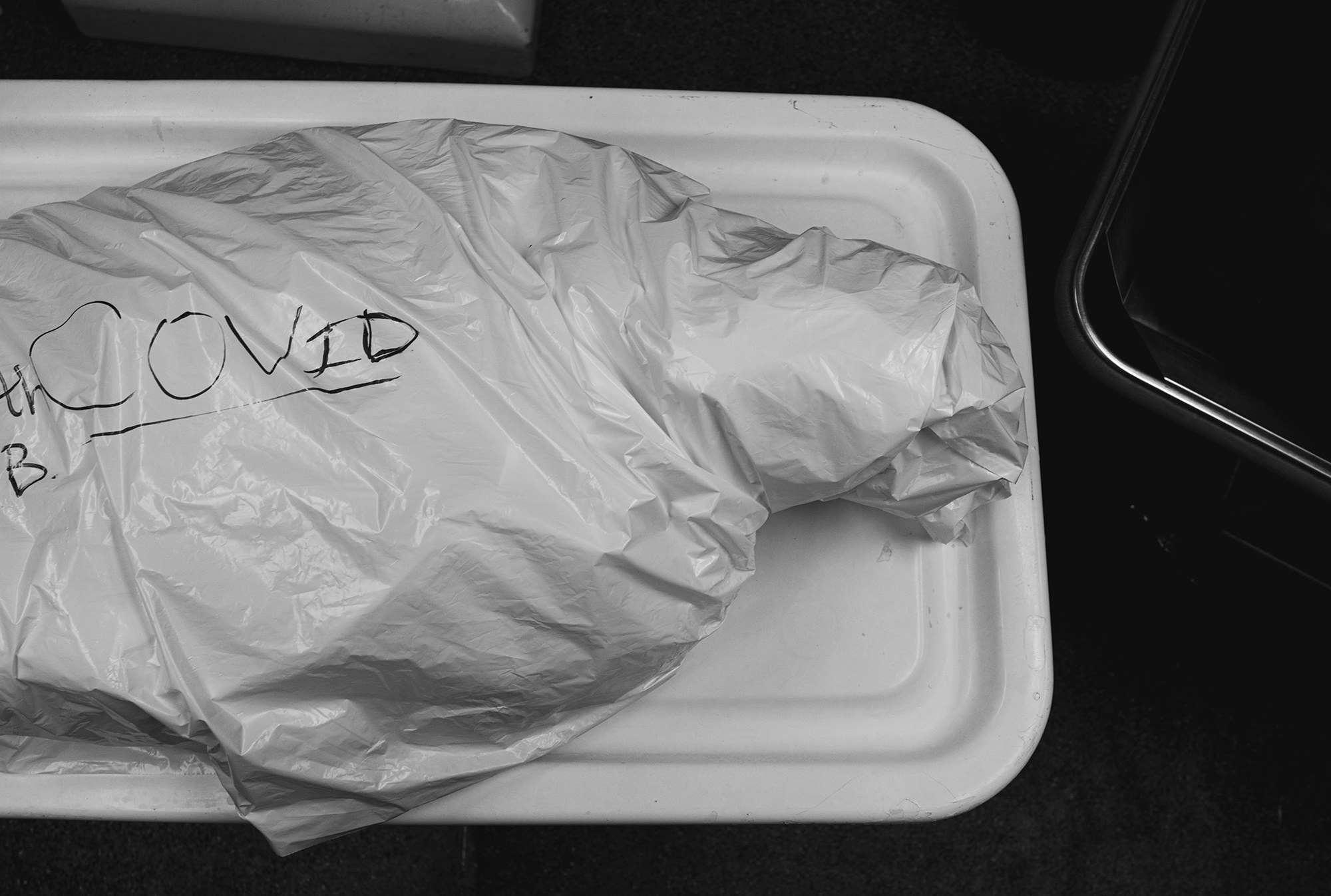 A body wrapped in plastic with the word &quot;COVID&quot; written on it 