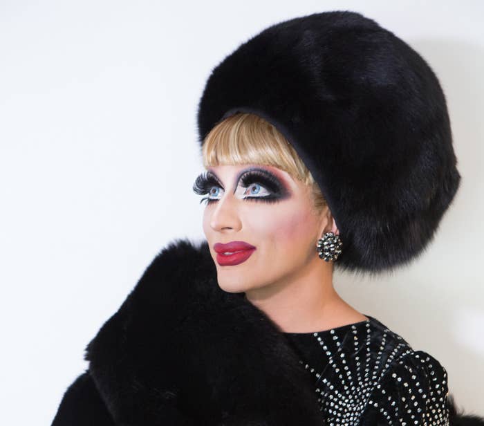 Bianca looking toward the upper left side while wearing a black fur stole with matching box hat