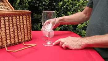 A model attaching a rubber band to a wine glass to secure a transparent lid to the top of the glass 
