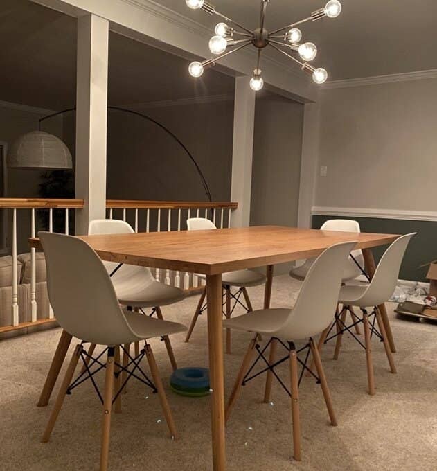 Reviewer's picture of the chair, which has wooden splayed legs linked with black wire, in gray