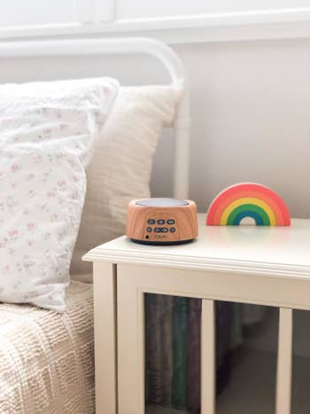reviewer pic of wooden white noise machine on wooden nightstand next to bed